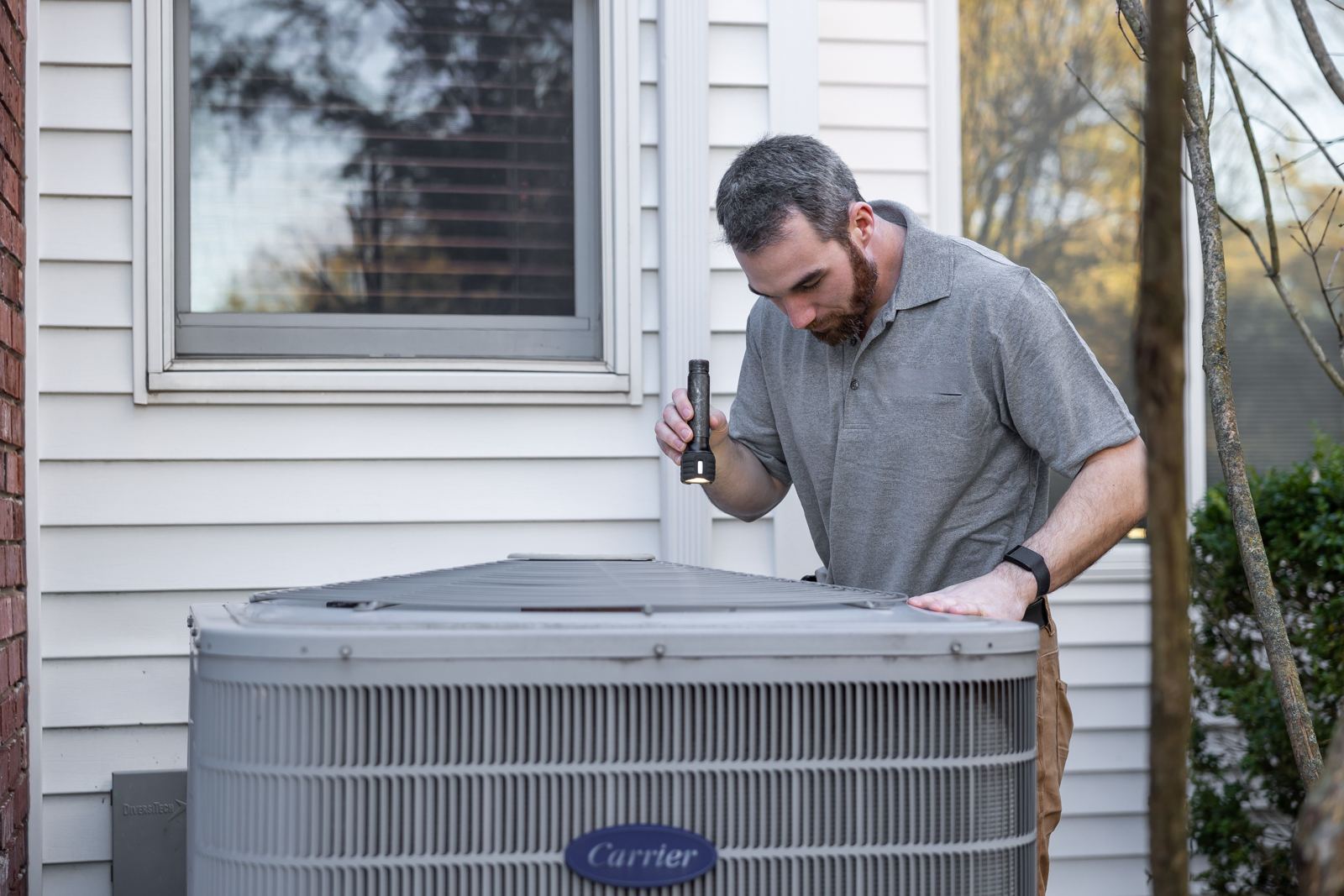 Residential air conditioning condenser beside the siding of a family home