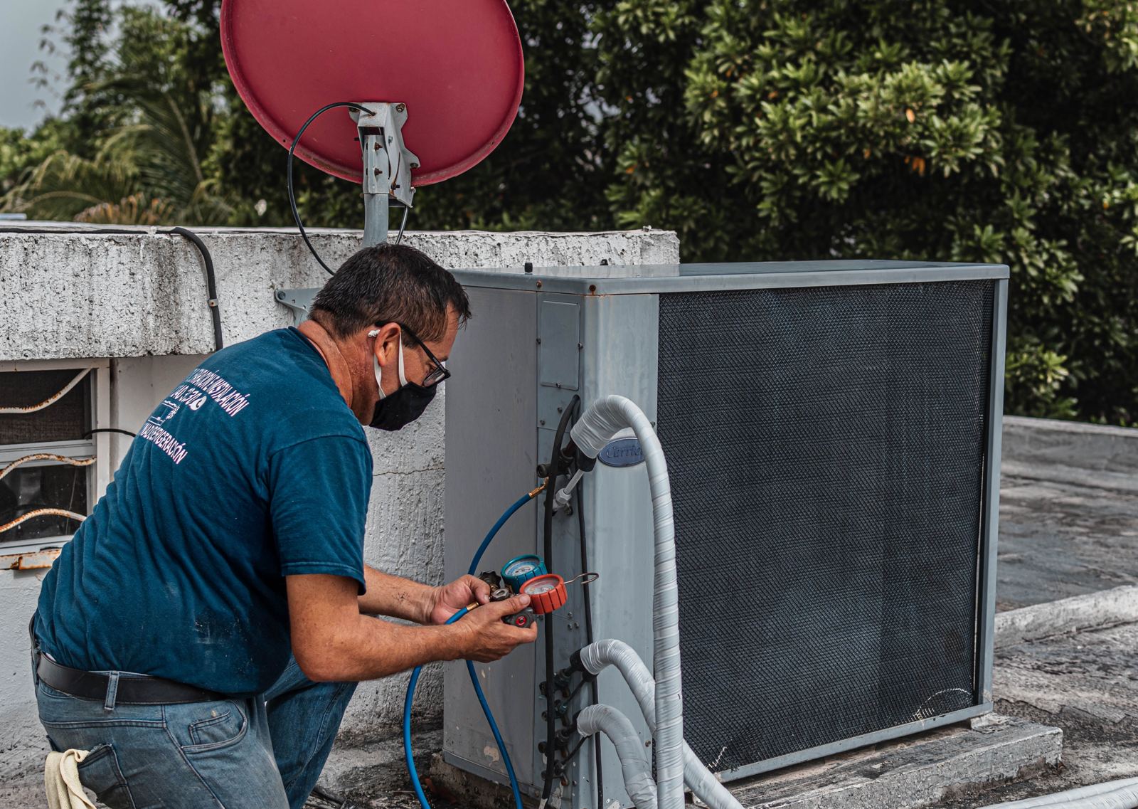 HVAC technician checking refrigerant pressures on a rooftop air conditioning condenser